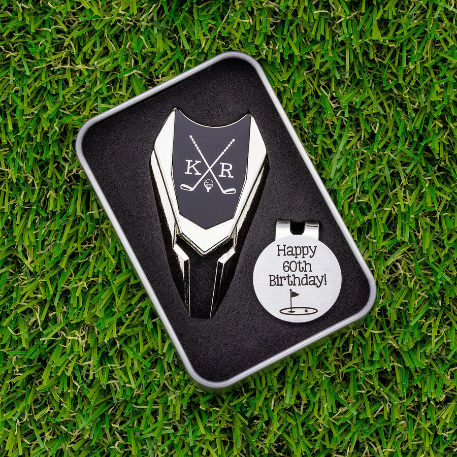 Golf ball marker and divot tool gift tin set personalized. Divot tool has crossed clubs with initials on each side. Round ball marker with hat clip has happy 60th birthday with golf flag graphic engraved.