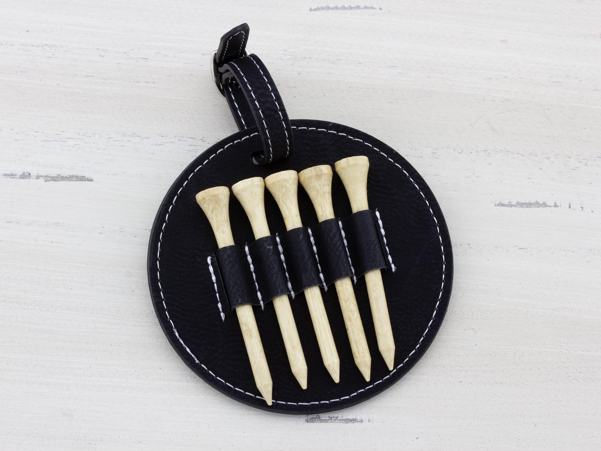 Black round leatherette golf bag tag with 5 golf tees on the back. Can be custom engraved with whatever you like.